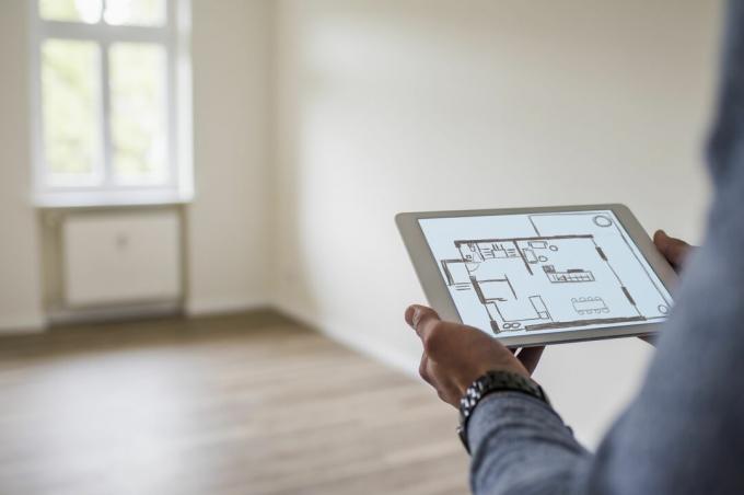 Mężczyzna w nowym domu gospodarstwa tablet wyświetlający cyfrowy plan piętra