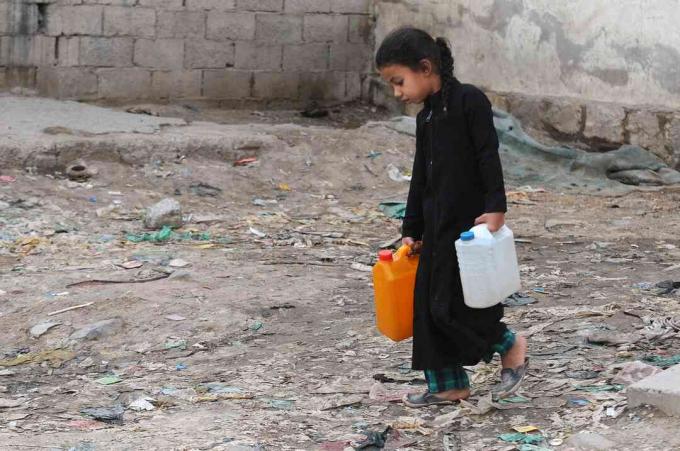 Mała dziewczynka nosi kanistry wypełnione czystą wodą z pompy charytatywnej podczas trwającego kryzysu czystej wody w Jemenie