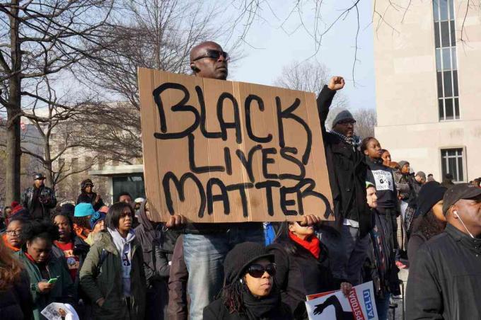 Mężczyzna protestujący przeciwko śmierci Michaela Browna, Erica Garnera i Tamira Rice'a pokazuje w Waszyngtonie Czarną sprawę.