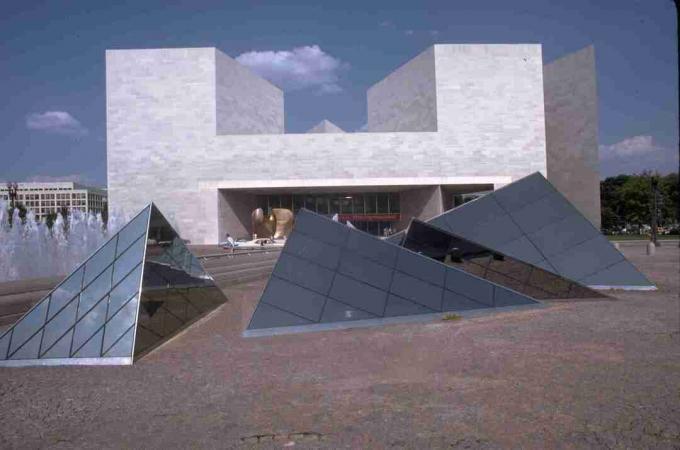 nowoczesny biały kamienny budynek w tle i szklane piramidy na ziemi na pierwszym planie