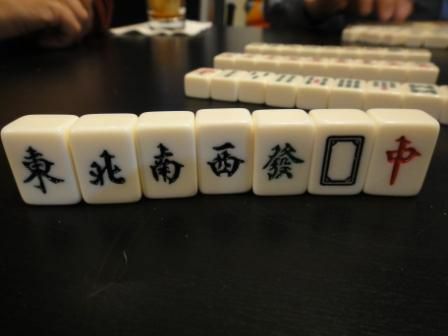 Płytki wiatrów i smoków w zestawie Mahjong stoją pionowo na stole.