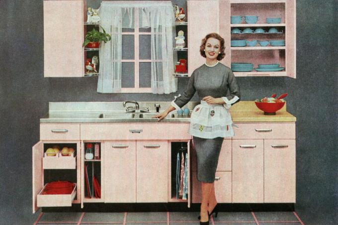 Vintage ilustracja modnej gospodyni stojącej przed jej nową różową kuchnią, 1957 r
