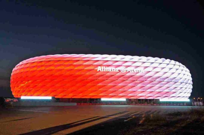 biały za dnia, wyrzeźbiona fasada Allianz Arena świeci w nocy na czerwono