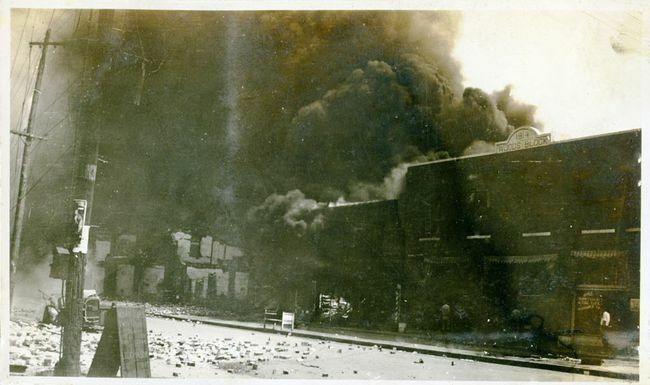 Uszkodzone nieruchomości i dym z budynków po masakrze w Tulsa Race, Tulsa, Oklahoma, czerwiec 1921.