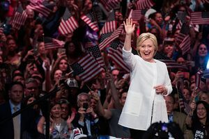 Hillary Clinton macha przed tłumem ludzi machających flagami USA