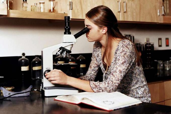 Nastolatka (14-16 lat) korzystająca z mikroskopów w klasie laboratorium naukowego