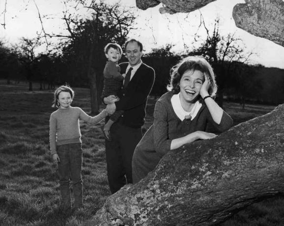 Czarno-białe zdjęcie Roalda Dahla trzymającego swoje dzieci; jego żona Patricia Neal opiera się na drzewie
