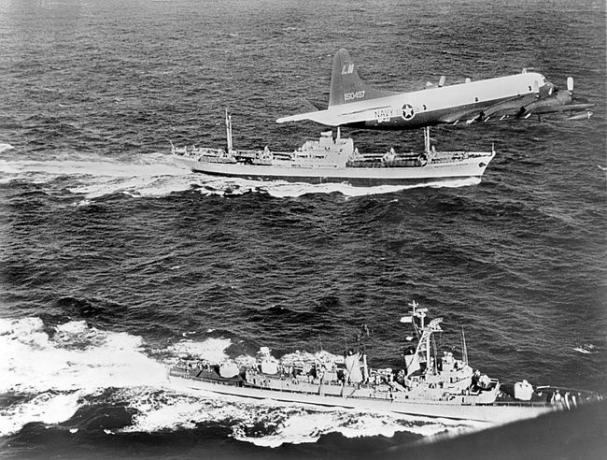 Z tyłu radziecki frachtowiec Anosow, eskortowany przez samolot marynarki wojennej i niszczyciel USS Barry, opuszcza Kubę podczas kryzysu kubańskiego w 1962 roku.