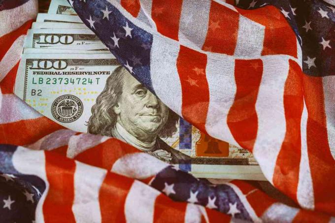 Flaga USA owinięta wokół banknotów stu dolarowych.