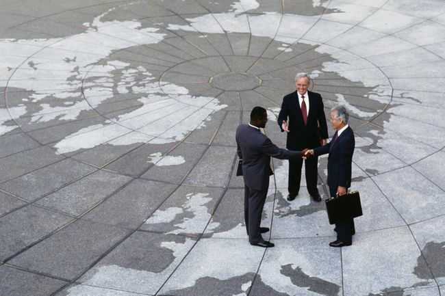  Regionalizm gospodarczy: Biznesmeni ściskający dłonie na mapie globu.
