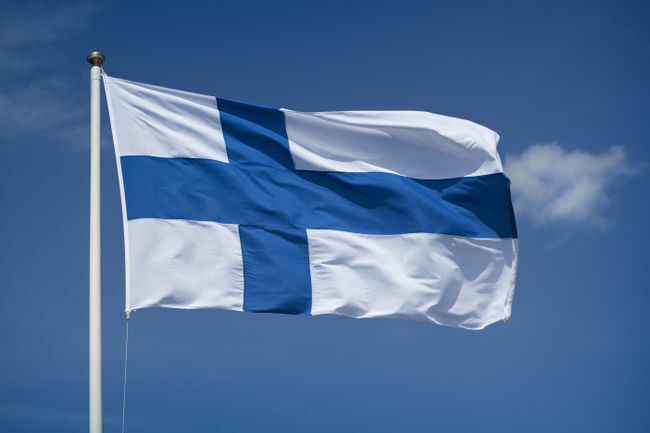 Podniesiona fińska flaga na niebieskim tle nieba