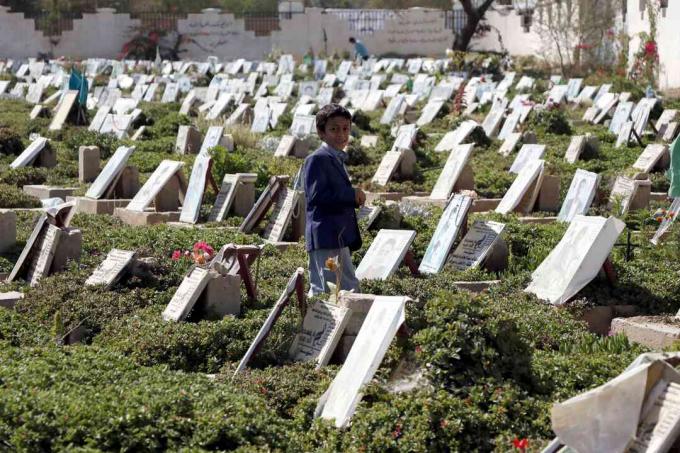 Dziecko spaceruje wśród grobów osób zabitych w toczącej się wojnie na cmentarzu w Sanie w Jemenie.