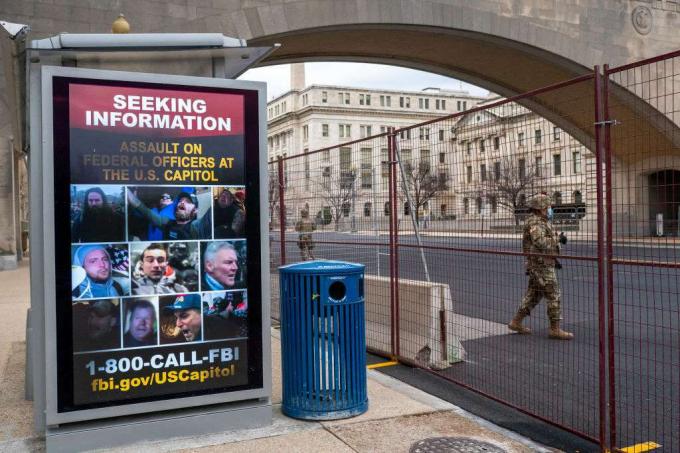 Gwardia Narodowa przechodzi obok plakatu szukającego informacji na temat ataku na Kapitol Stanów Zjednoczonych 19 stycznia 2021 roku.