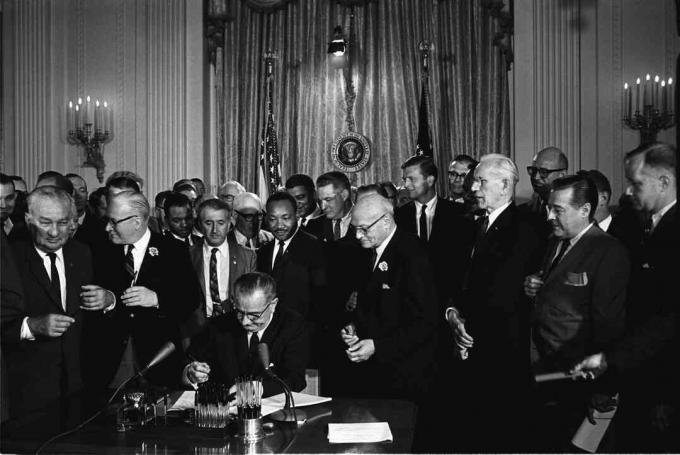 Prezydent Lyndon B. Johnson podpisuje ustawę o prawach obywatelskich z 1964 r., Na co patrzą Martin Luther King Jr. i inni.